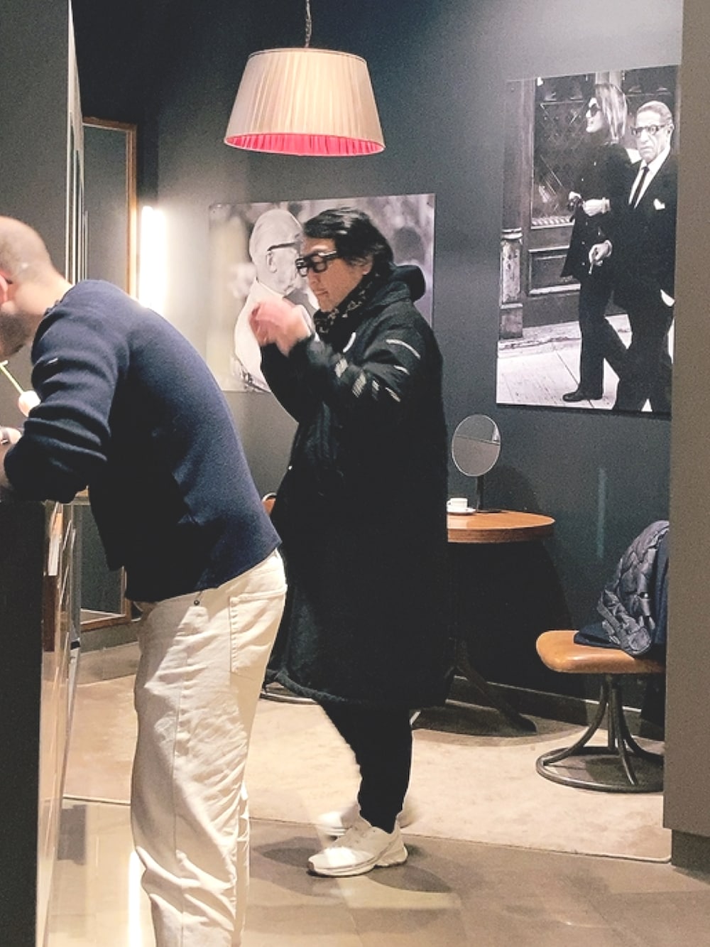 ブラック系のステンカラーコート、ホワイト系のスニーカー、ブラック系のストール/ショールを着用したメンズの秋コーディネートの2枚目の写真