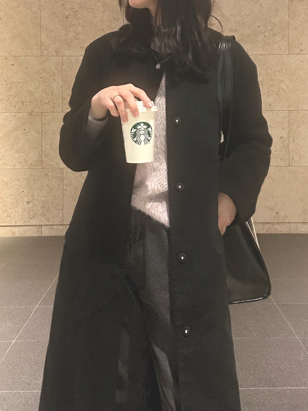 ブラック系のノーカラーコート、パープル系のニット/セーター、グレー系のデニムパンツを着用したレディースの冬コーディネートの2枚目の写真