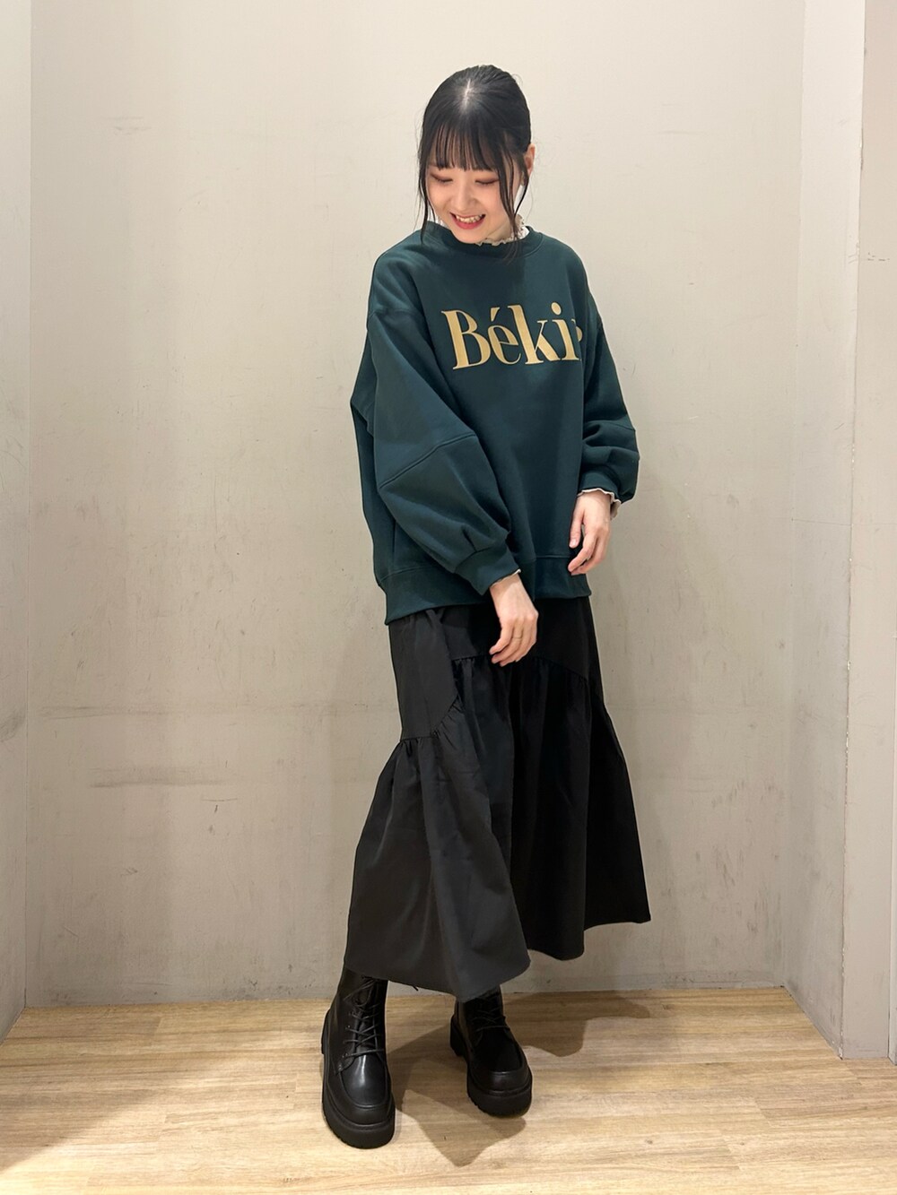 グリーン系のスウェット、ブラック系のスカートを着用したレディースの冬コーディネートの2枚目の写真