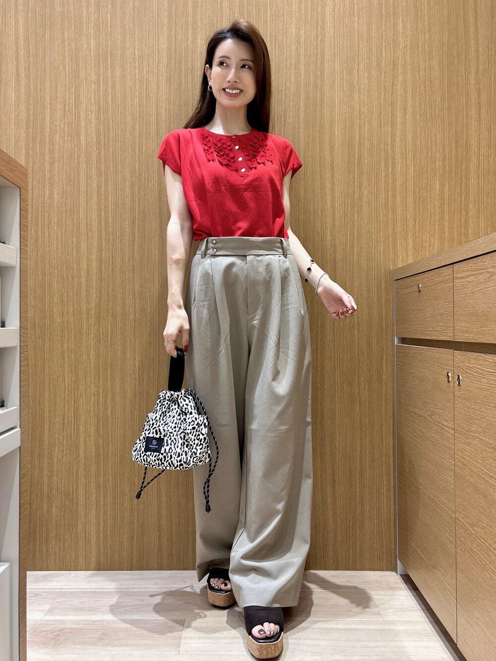 レッド系のニット/セーター、ブラウン系のその他パンツ、ベージュ系のショルダーバッグを着用したレディースの夏コーディネートの8枚目の写真