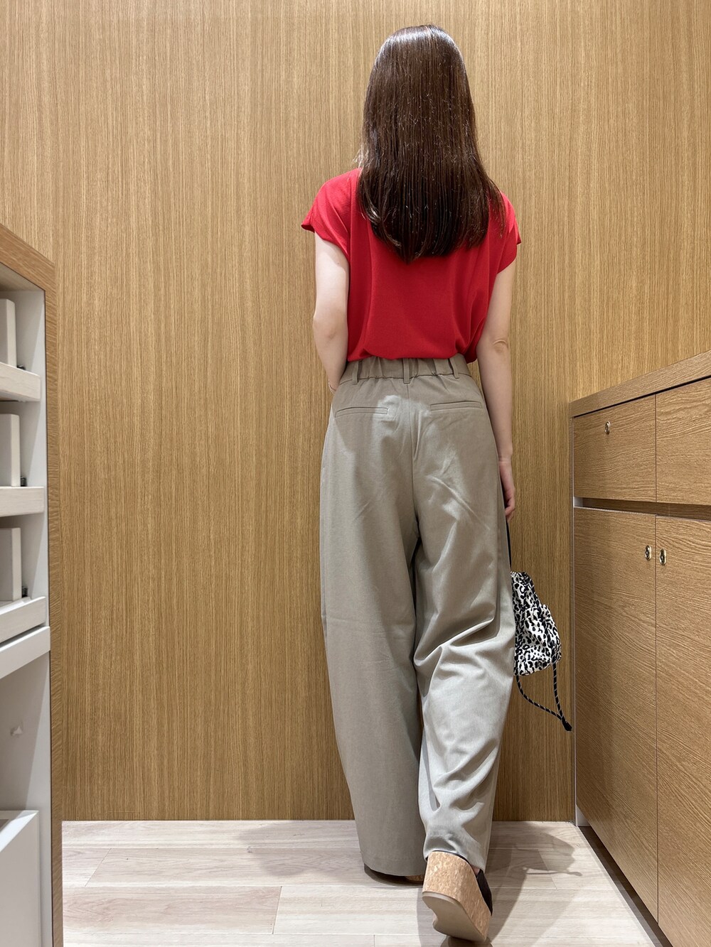 レッド系のニット/セーター、ブラウン系のその他パンツ、ベージュ系のショルダーバッグを着用したレディースの夏コーディネートの9枚目の写真