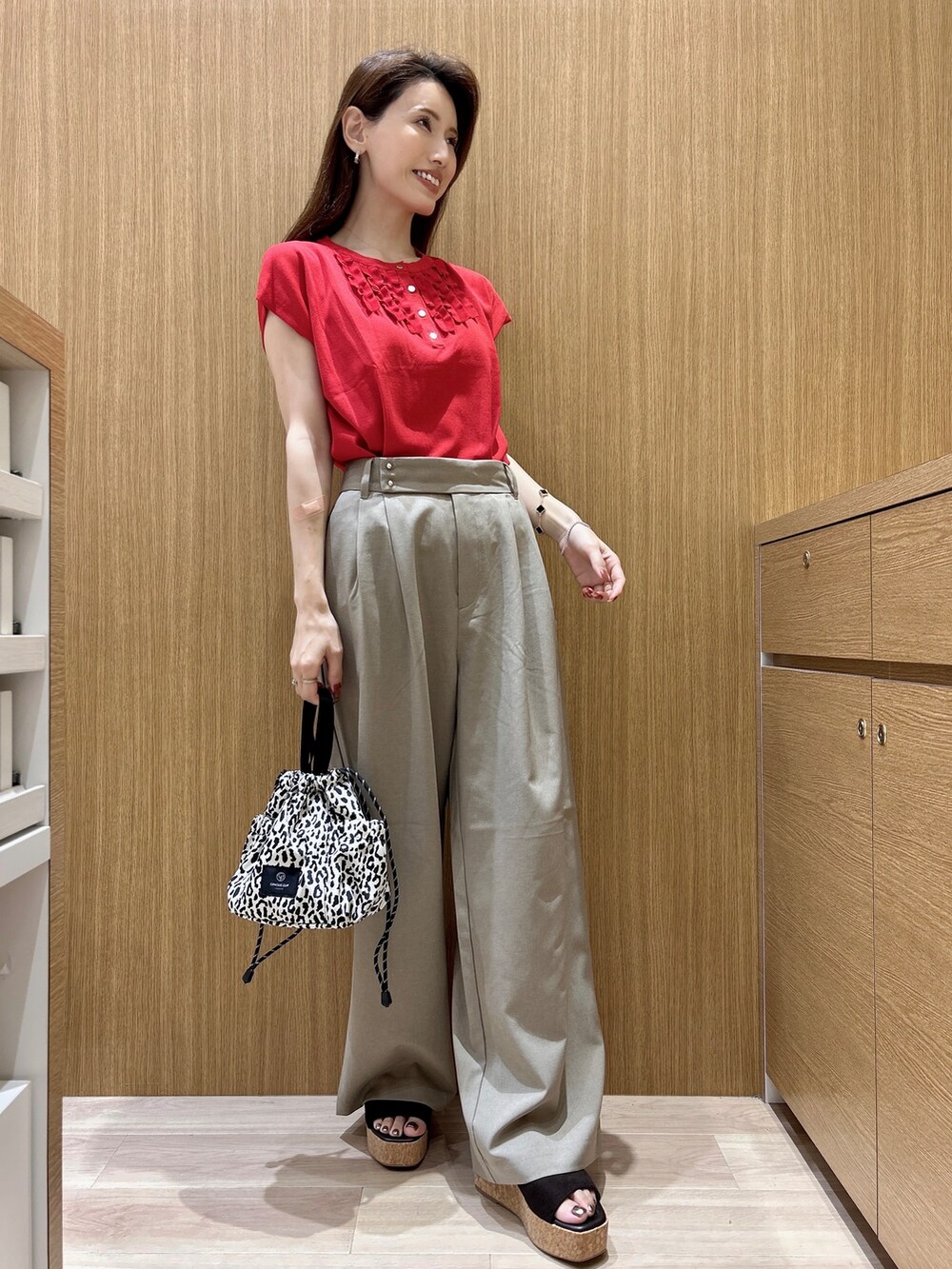 レッド系のニット/セーター、ブラウン系のその他パンツ、ベージュ系のショルダーバッグを着用したレディースの夏コーディネートの10枚目の写真