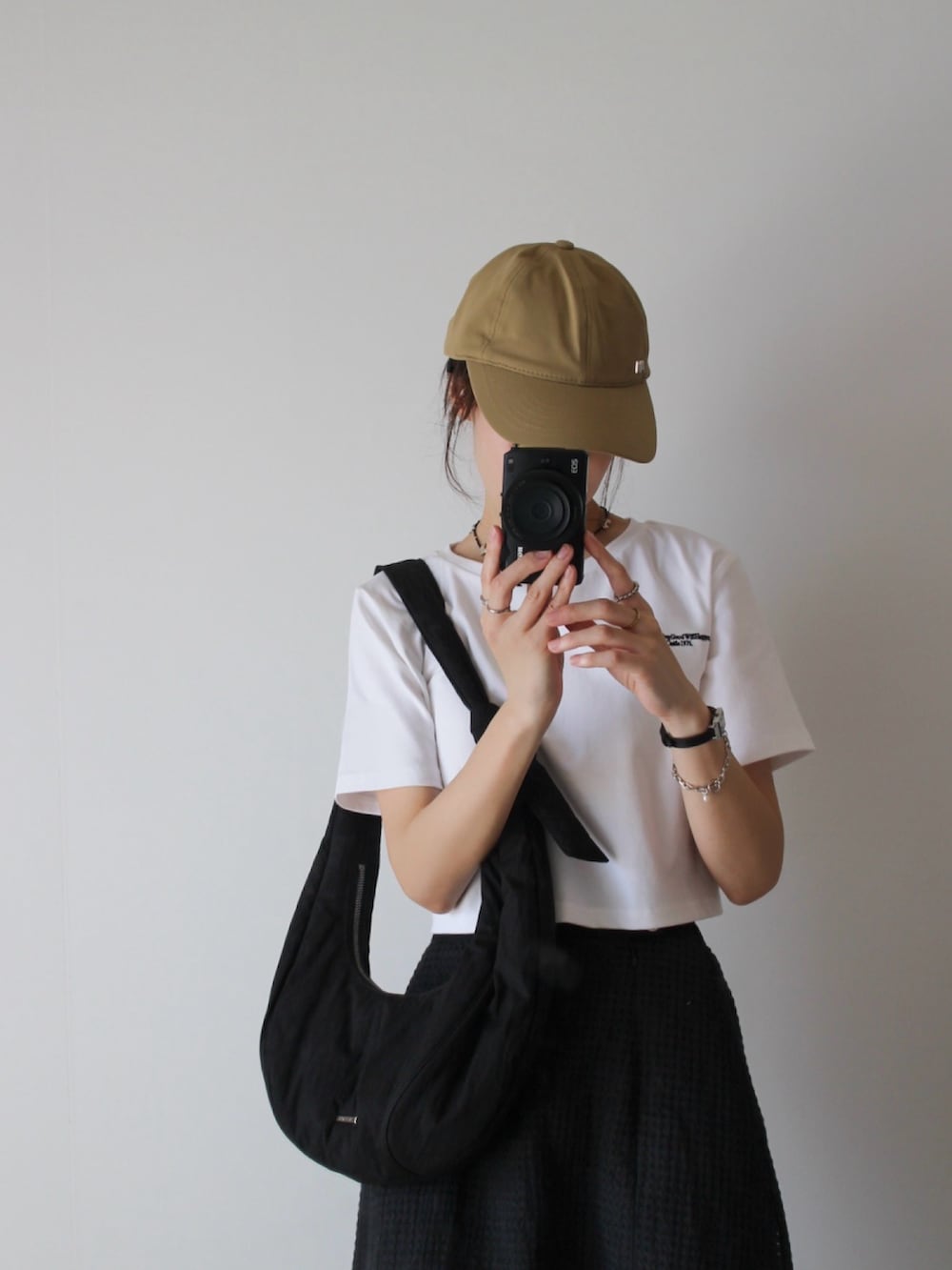 ホワイト系のTシャツ/カットソー、ブラック系のスカート、ブラック系のスニーカーを着用したレディースの夏コーディネートの2枚目の写真