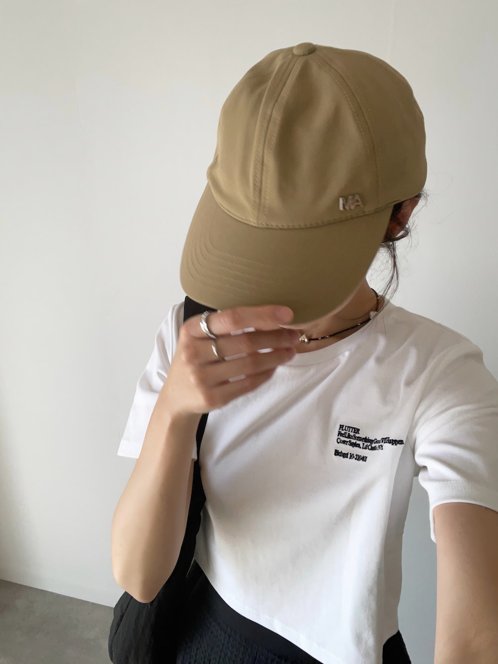 ホワイト系のTシャツ/カットソー、ブラック系のスカート、ブラック系のスニーカーを着用したレディースの夏コーディネートの3枚目の写真
