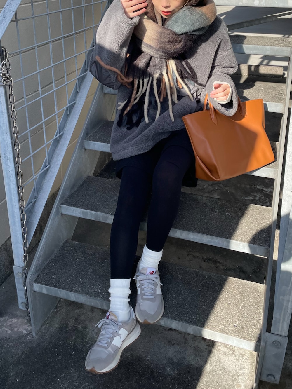 イエロー系のトートバッグ、グレー系のスニーカー、ブラック系のその他パンツを着用したレディースの冬コーディネートの2枚目の写真