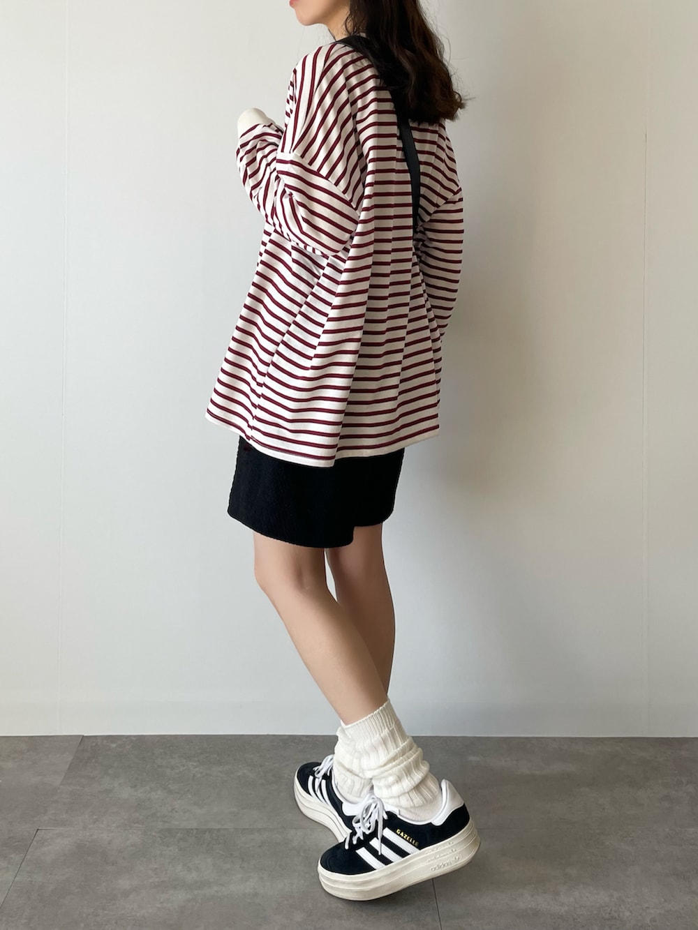 ブラック系のショルダーバッグ、レッド系のTシャツ/カットソー、ブラック系のスニーカーを着用したレディースの春コーディネートの2枚目の写真