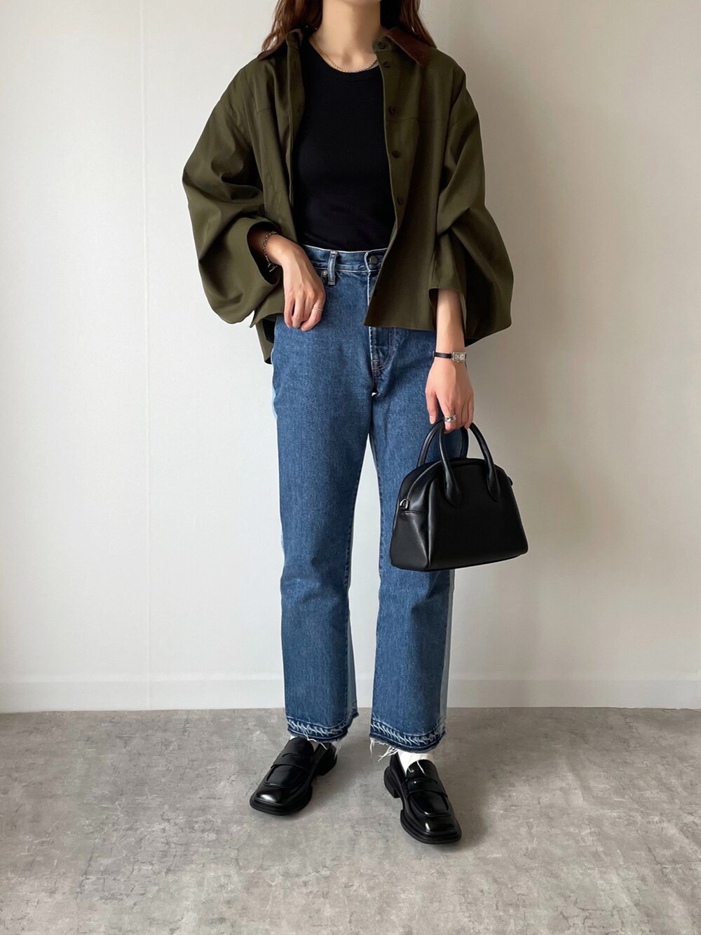 ブラック系のローファー、ブラック系のボストンバッグ、ブルー系のデニムパンツを着用したレディースの夏コーディネートの3枚目の写真
