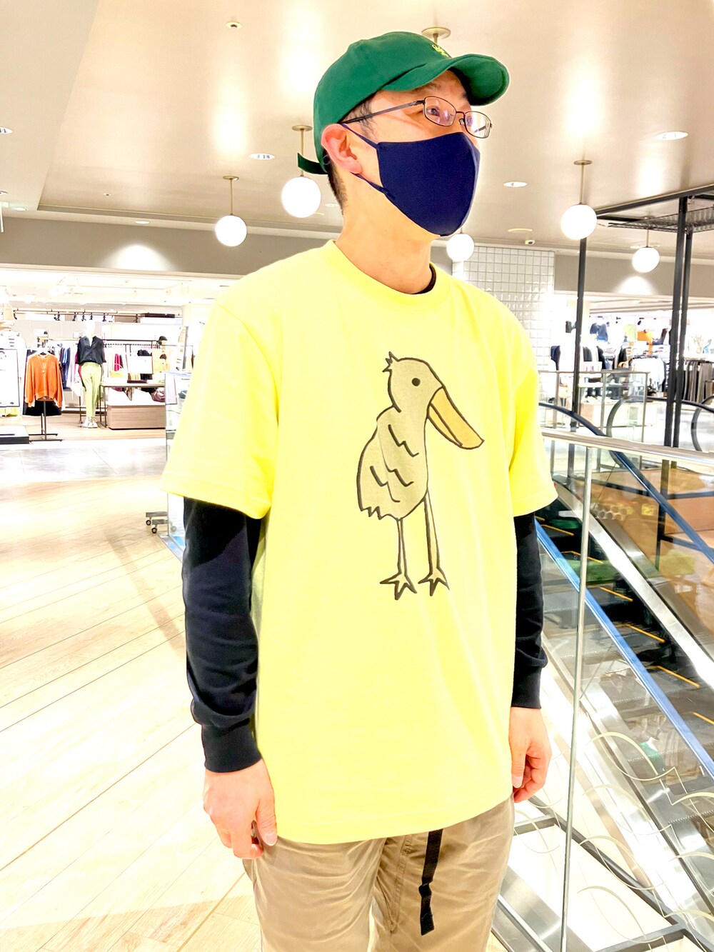 イエロー系のTシャツ/カットソー、グリーン系のチノパンツ、グリーン系のキャップを着用したメンズの春コーディネートの2枚目の写真