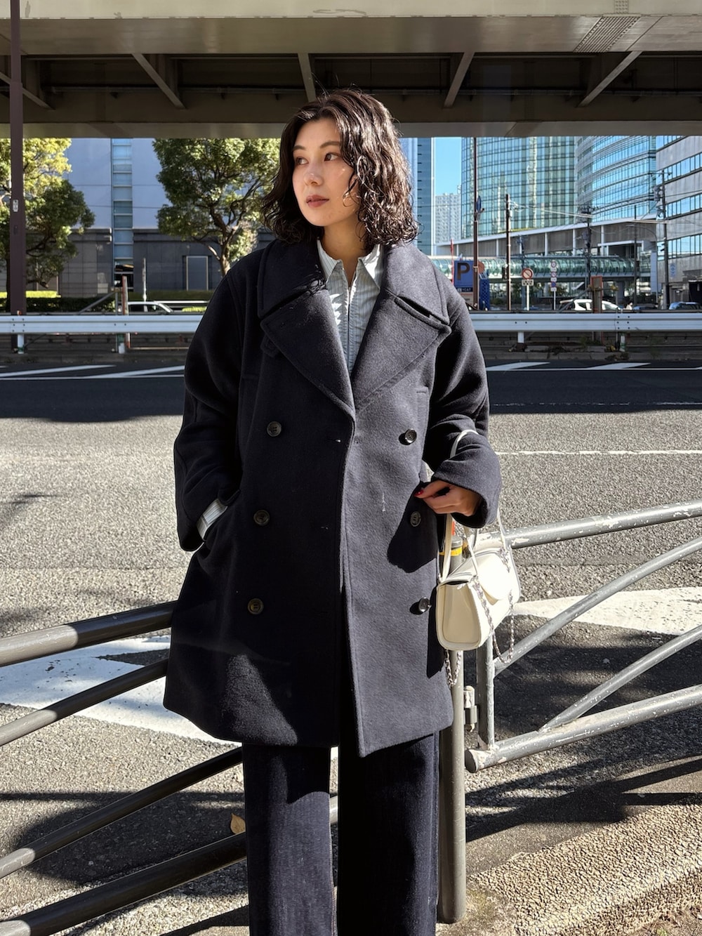 ブルー系のデニムパンツ、ホワイト系のショルダーバッグ、ブルー系のピーコートを着用したレディースの冬コーディネートの2枚目の写真