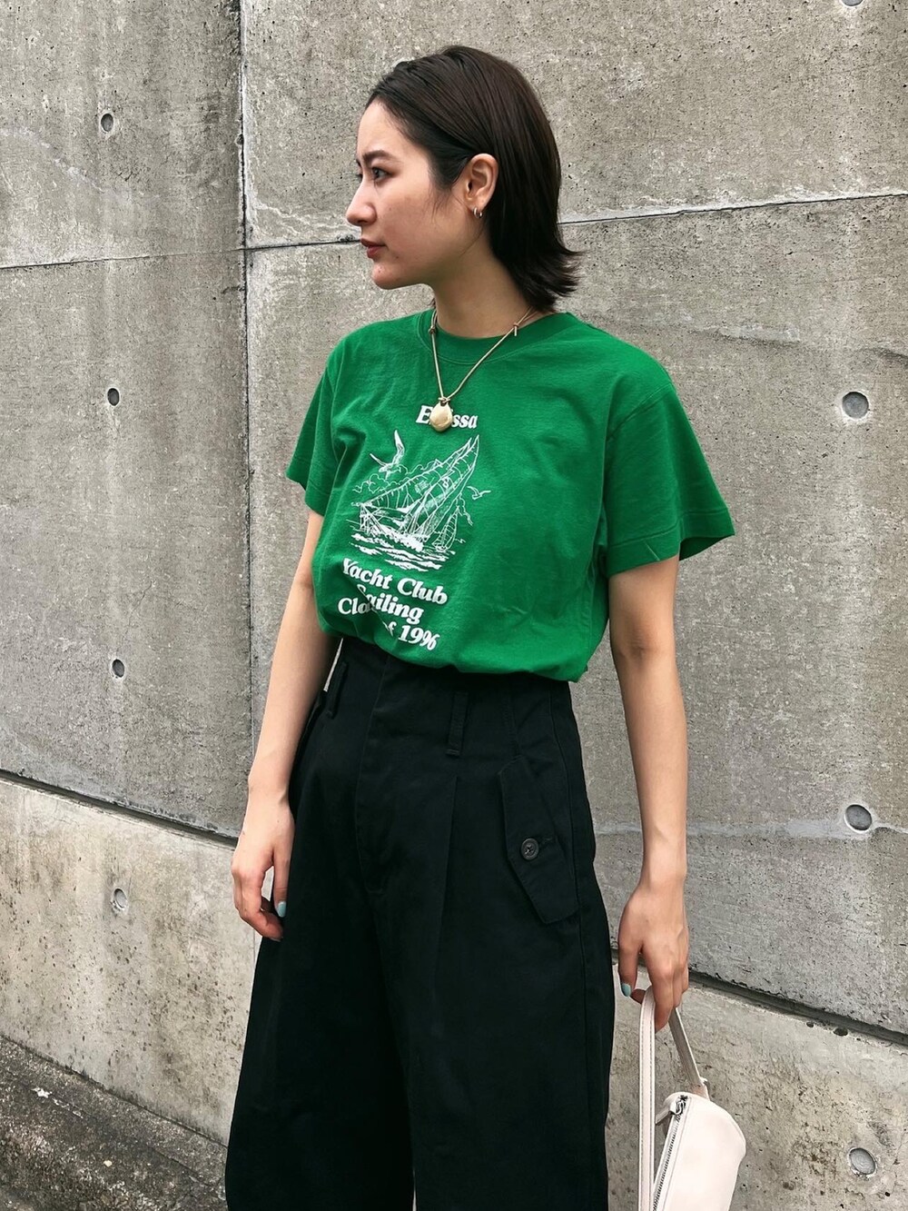 グリーン系のTシャツ/カットソー、ブラック系のデニムパンツ、ホワイト系のハンドバッグを着用したレディースの夏コーディネートの2枚目の写真