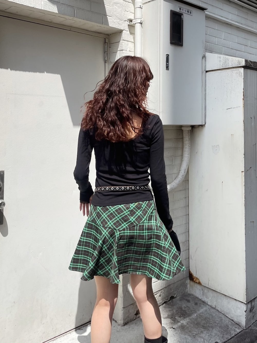 ブラック系のTシャツ/カットソー、グリーン系のスカート、ブラック系のブーツを着用したレディースの秋コーディネートの3枚目の写真