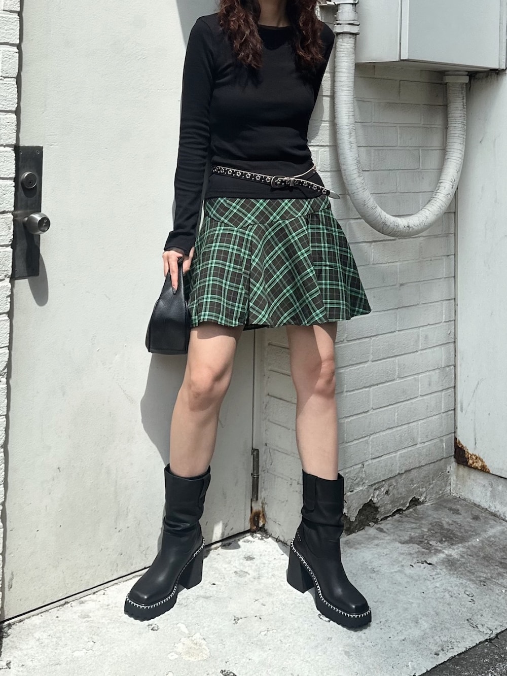 ブラック系のTシャツ/カットソー、グリーン系のスカート、ブラック系のブーツを着用したレディースの秋コーディネートの2枚目の写真