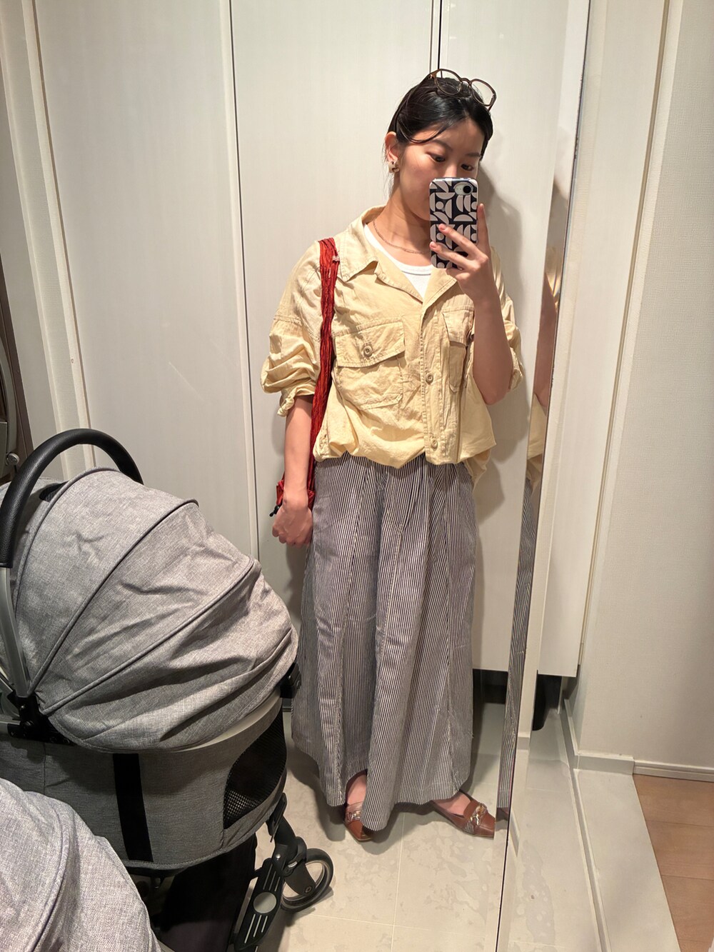 ブルー系のスカート、ベージュ系のシャツ/ブラウス、レッド系のエコバッグ/サブバッグを着用したレディースの夏コーディネートの2枚目の写真