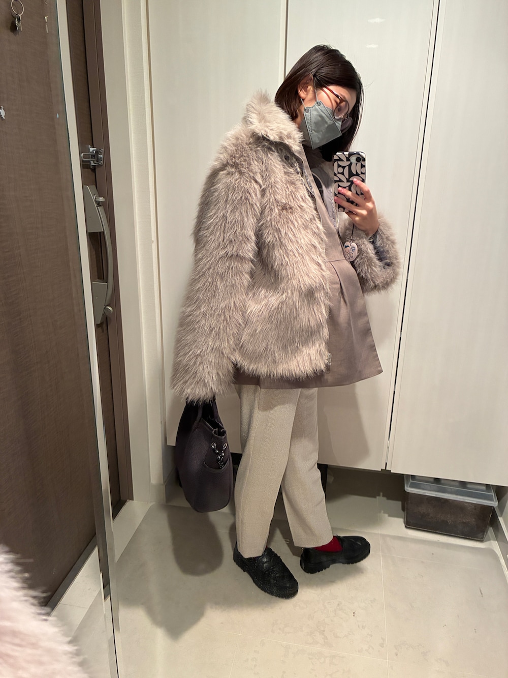 グレー系のベスト、グレー系のショルダーバッグ、ベージュ系のパンツを着用したレディースの春コーディネートの2枚目の写真