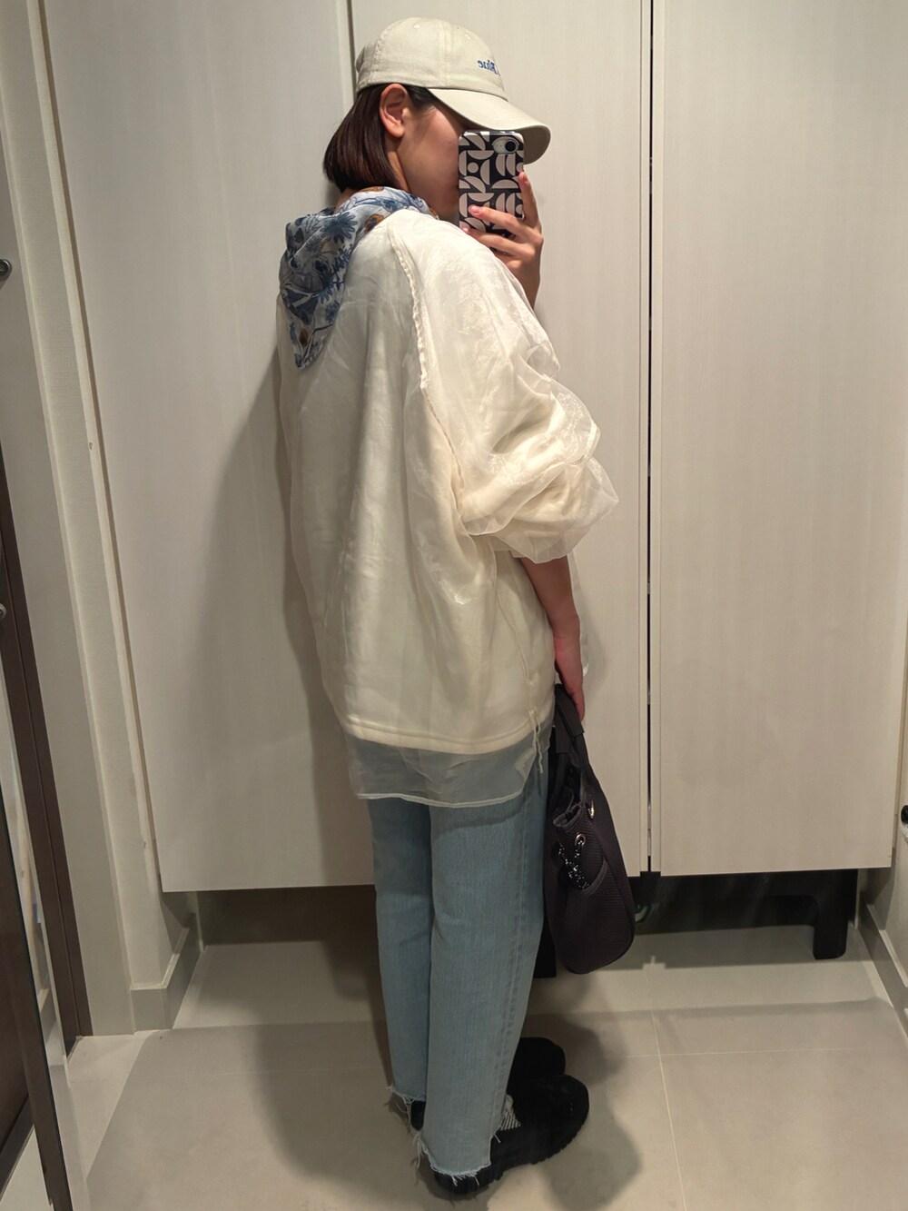 グレー系のショルダーバッグ、ホワイト系のスウェット、ブルー系のデニムパンツを着用したレディースの春コーディネートの2枚目の写真