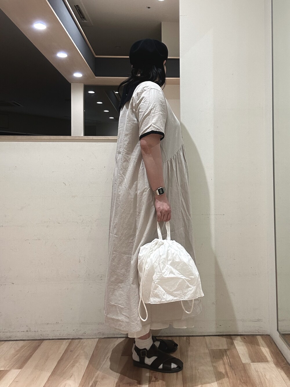 ホワイト系のワンピース、ホワイト系のハンドバッグ、ブラウン系のサンダルを着用したレディースの春コーディネートの2枚目の写真