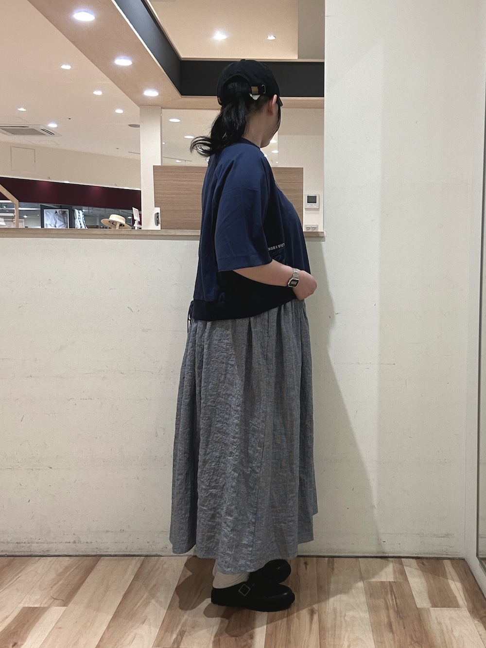 ホワイト系のハンドバッグ、ブラック系のドレスシューズ、ブルー系のスカートを着用したレディースの春コーディネートの2枚目の写真