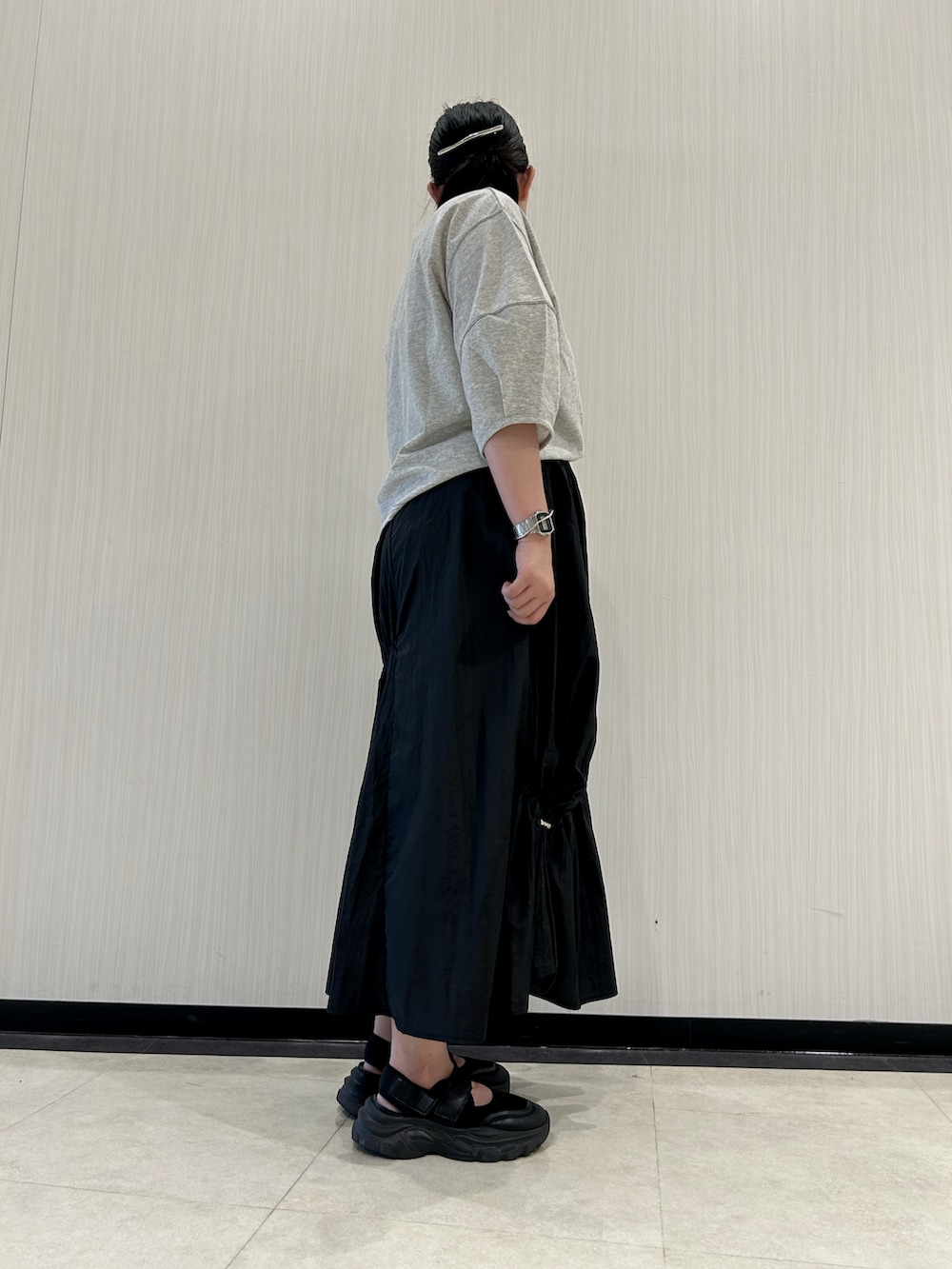 ブラック系のスカート、ブラック系のサンダル、グレー系のTシャツ/カットソーを着用したレディースの夏コーディネートの3枚目の写真