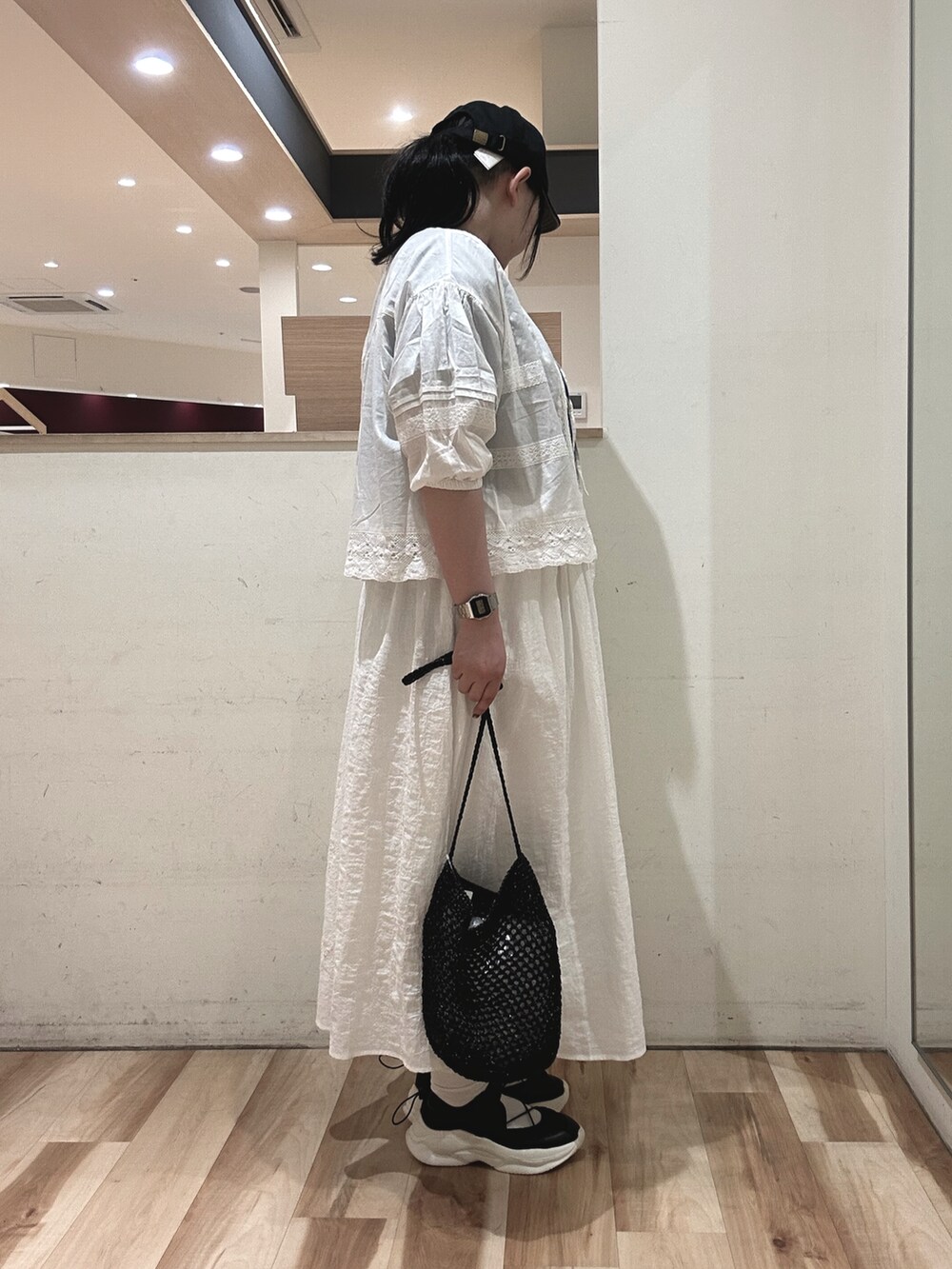 ブラック系のハンドバッグ、ブラック系のスニーカー、ホワイト系のシャツ/ブラウスを着用したレディースの春コーディネートの2枚目の写真