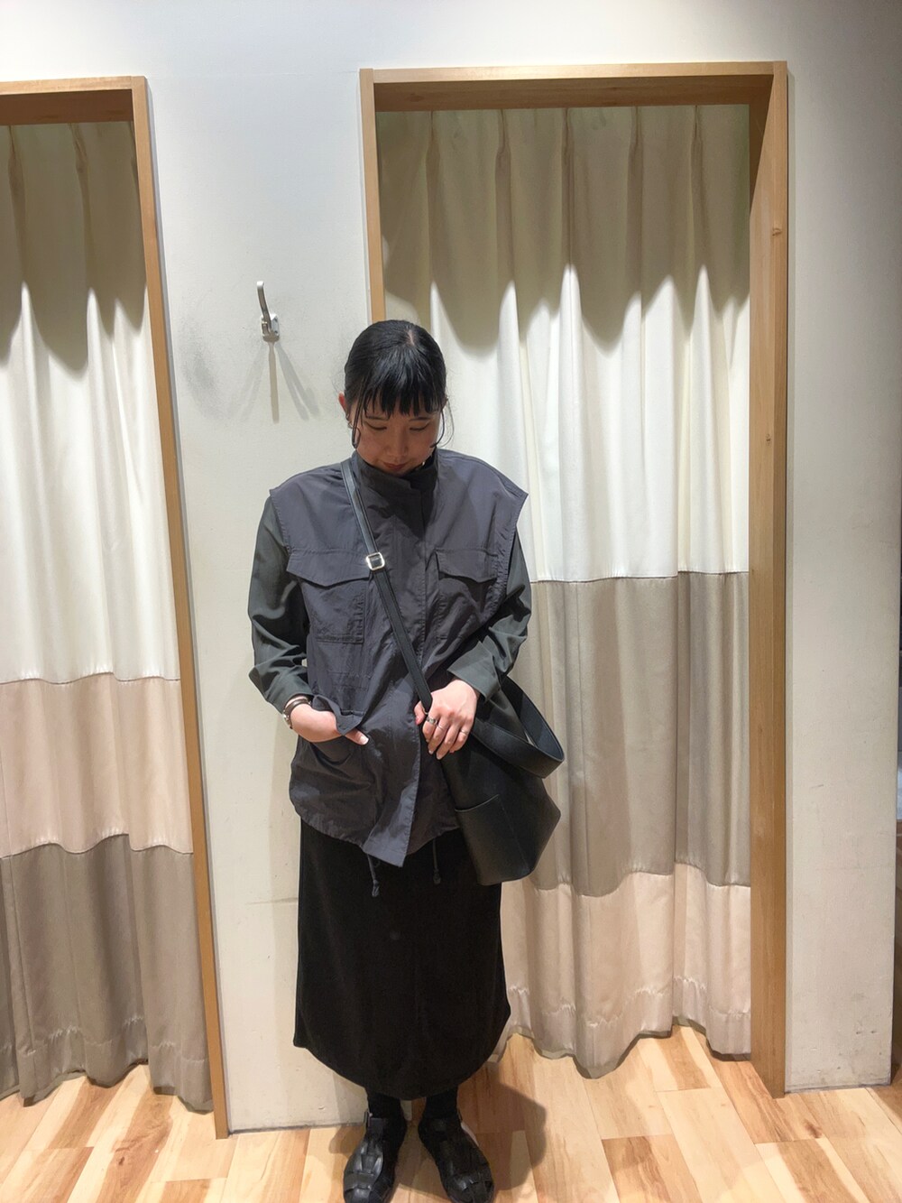 グレー系のベスト、グレー系のシャツ/ブラウス、ブラック系のハンドバッグを着用したレディースの春コーディネートの2枚目の写真