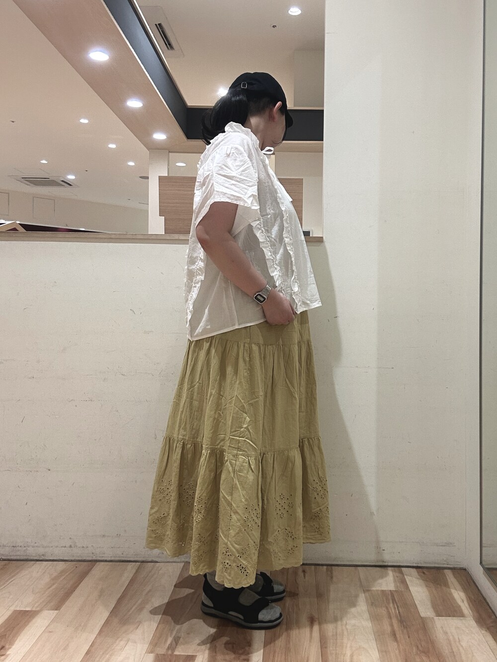 ブラック系のハンドバッグ、ブラック系のサンダル、イエロー系のスカートを着用したレディースの春コーディネートの2枚目の写真