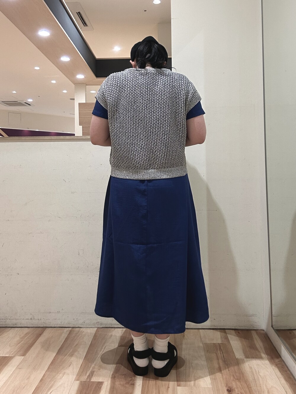 グレー系のニット/セーター、ブルー系のワンピース、ブラック系のハンドバッグを着用したレディースの春コーディネートの3枚目の写真