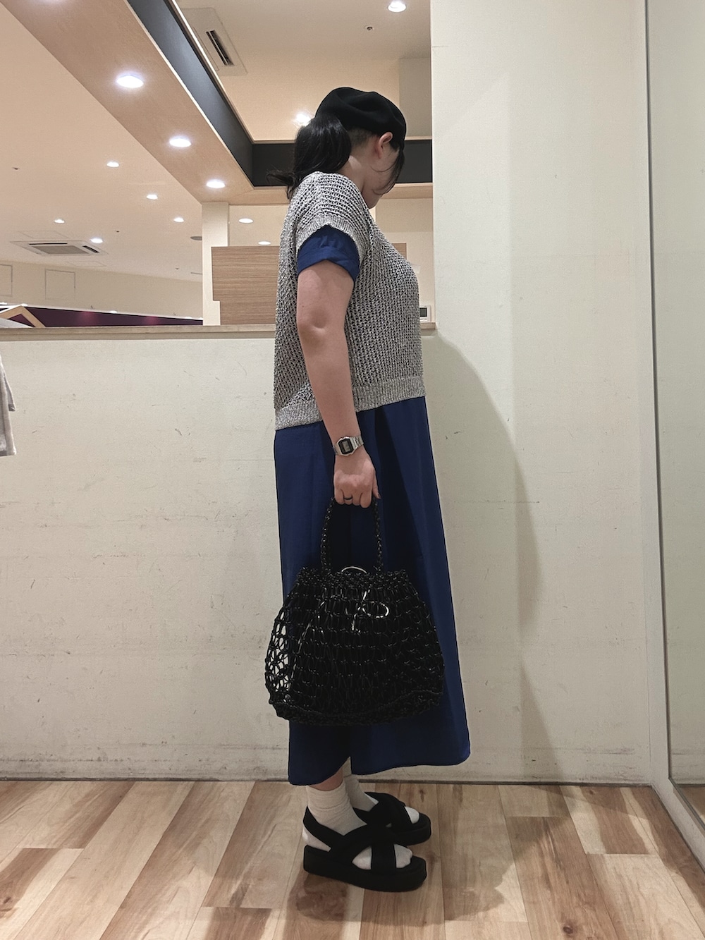 グレー系のニット/セーター、ブルー系のワンピース、ブラック系のハンドバッグを着用したレディースの春コーディネートの2枚目の写真