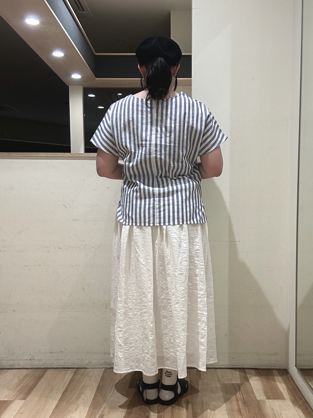 ブラック系のサンダル、ブラウン系のハンドバッグ、ホワイト系のスカートを着用したレディースの春コーディネートの3枚目の写真