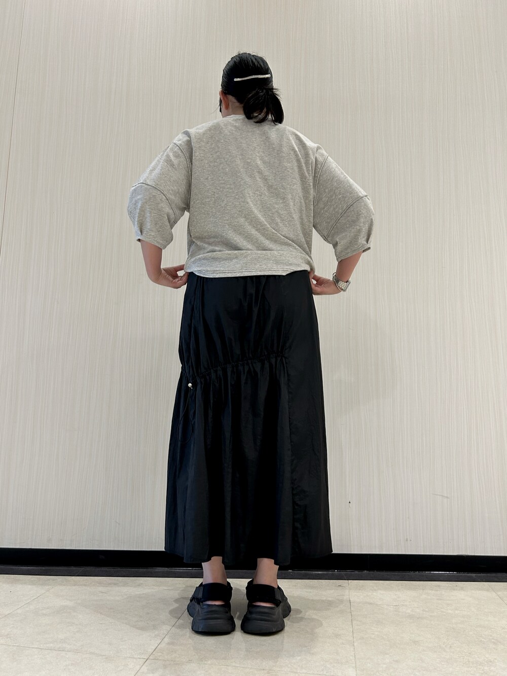 ブラック系のスカート、ブラック系のサンダル、グレー系のTシャツ/カットソーを着用したレディースの夏コーディネートの5枚目の写真