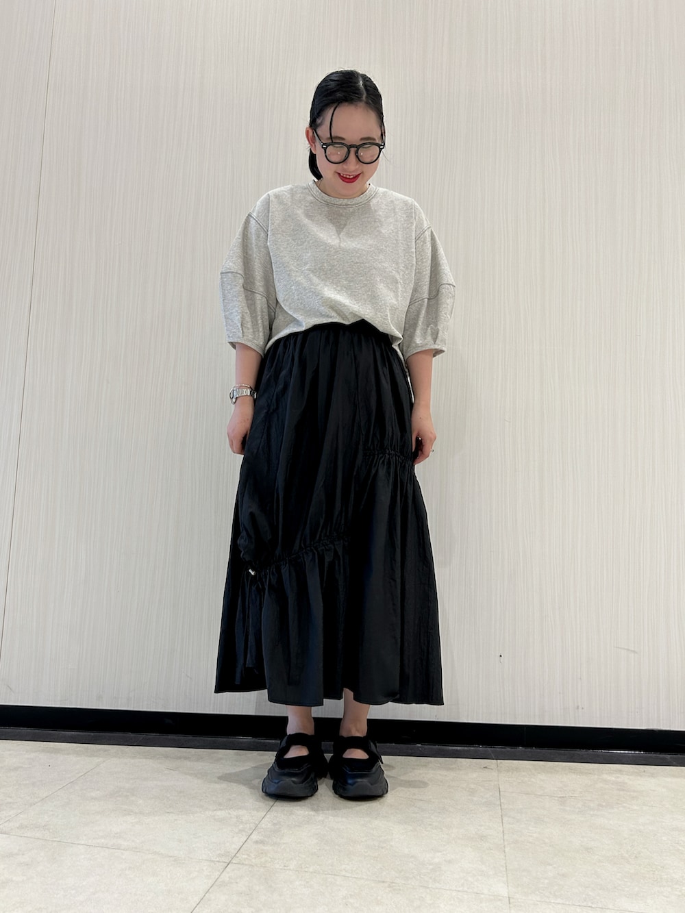 ブラック系のスカート、ブラック系のサンダル、グレー系のTシャツ/カットソーを着用したレディースの夏コーディネートの2枚目の写真