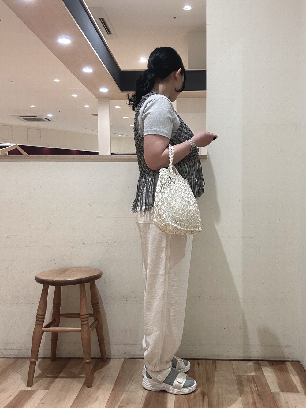 ホワイト系のハンドバッグ、グレー系のベスト、ブルー系のTシャツ/カットソーを着用したレディースの春コーディネートの2枚目の写真