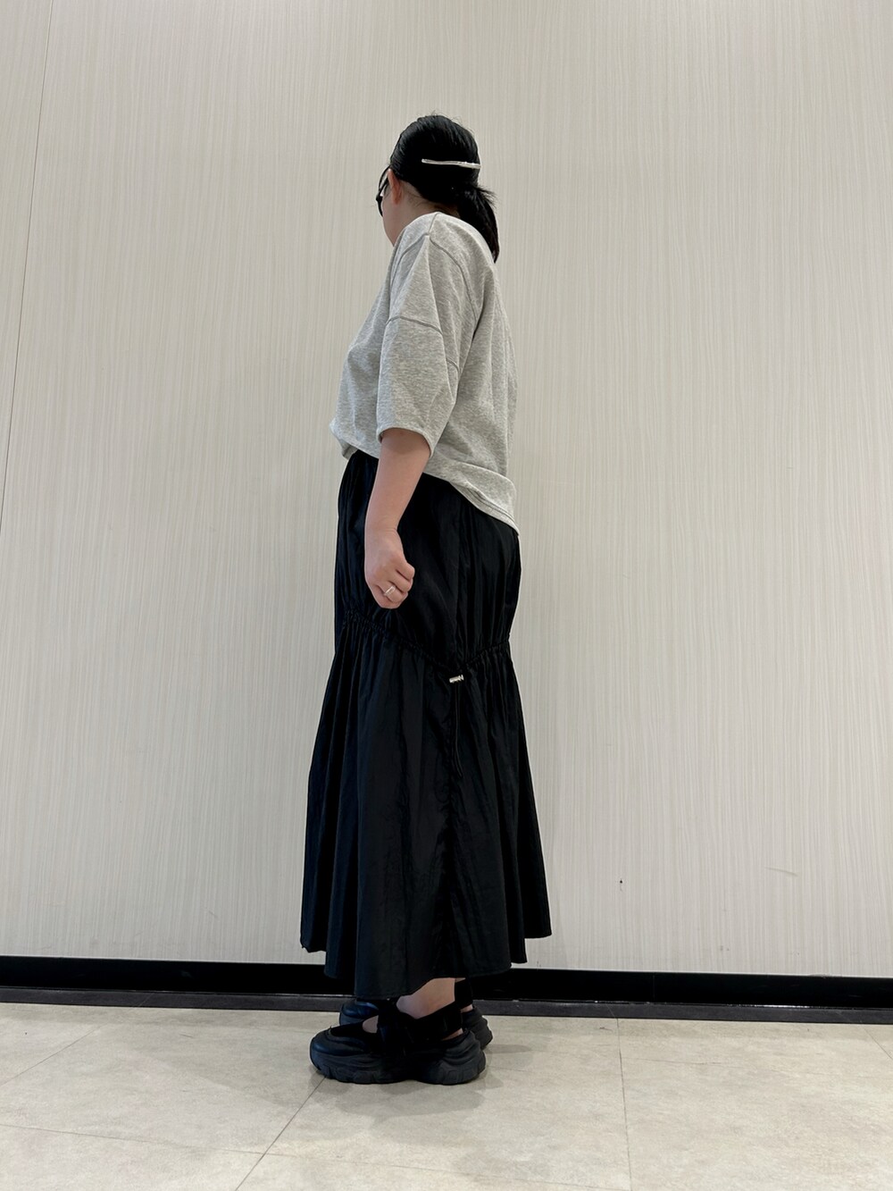 ブラック系のスカート、ブラック系のサンダル、グレー系のTシャツ/カットソーを着用したレディースの夏コーディネートの4枚目の写真