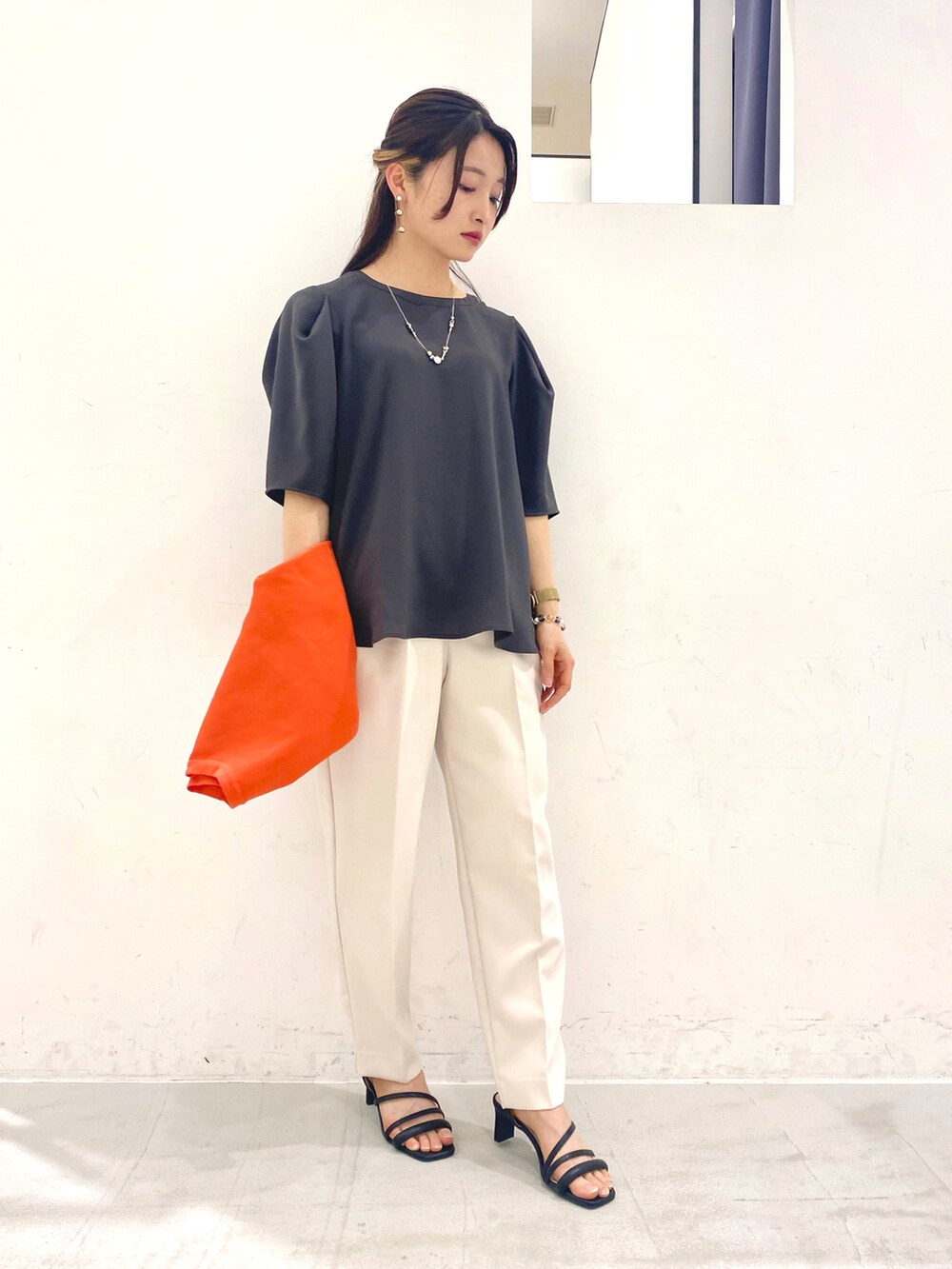 グレー系のトップス、オレンジ系のカーディガン/ボレロ、ベージュ系のその他パンツを着用したレディースの春コーディネートの3枚目の写真