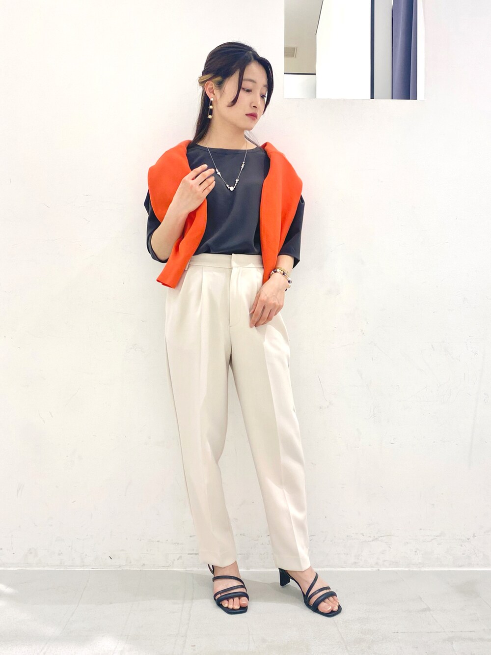 グレー系のトップス、オレンジ系のカーディガン/ボレロ、ベージュ系のその他パンツを着用したレディースの春コーディネートの2枚目の写真