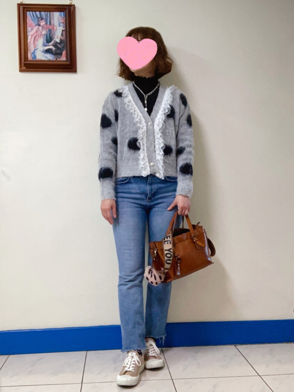 ブラウン系のショルダーバッグ、グレー系のノーカラージャケット、ブルー系のデニムパンツを着用したレディースの冬コーディネートの2枚目の写真