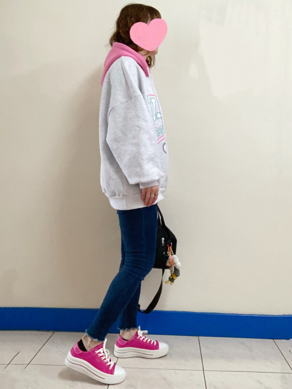 ホワイト系のパーカー、ブラック系のバッグ、ブルー系のデニムパンツを着用したレディースの冬コーディネートの2枚目の写真