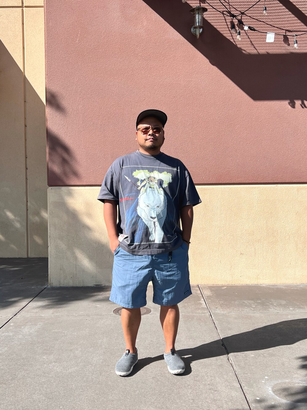 ブラック系のTシャツ/カットソー、ブルー系のパンツ、グレー系のスニーカーを着用したメンズの夏コーディネートの2枚目の写真