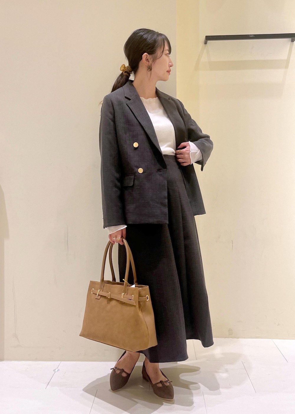 ブラック系のスカート、ブラック系のテーラードジャケット、ホワイト系のTシャツ/カットソーを着用したレディースの秋コーディネートの2枚目の写真