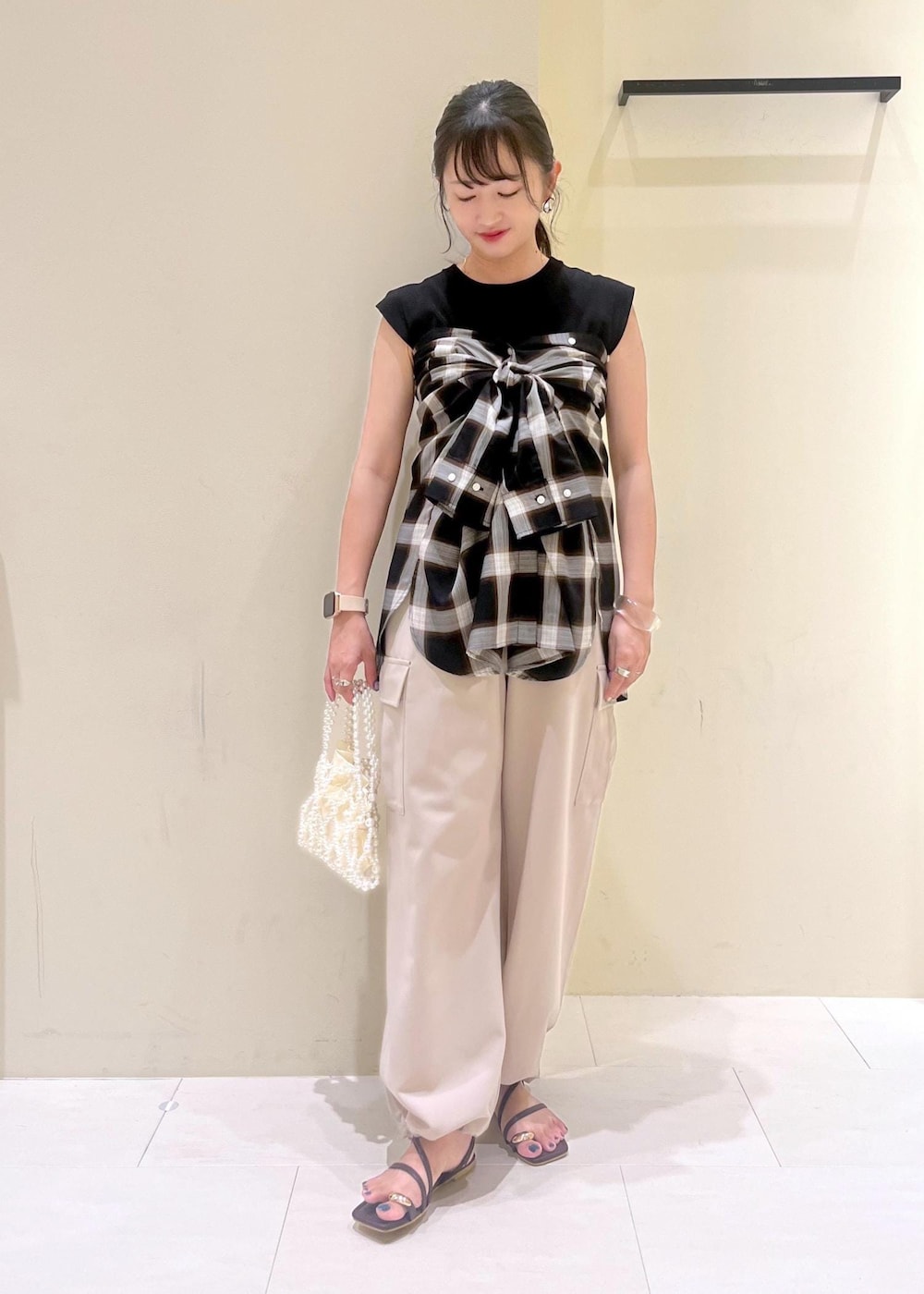 ブラック系のニット/セーター、ベージュ系のカーゴパンツ、ブラウン系のサンダルを着用したレディースの夏コーディネートの2枚目の写真