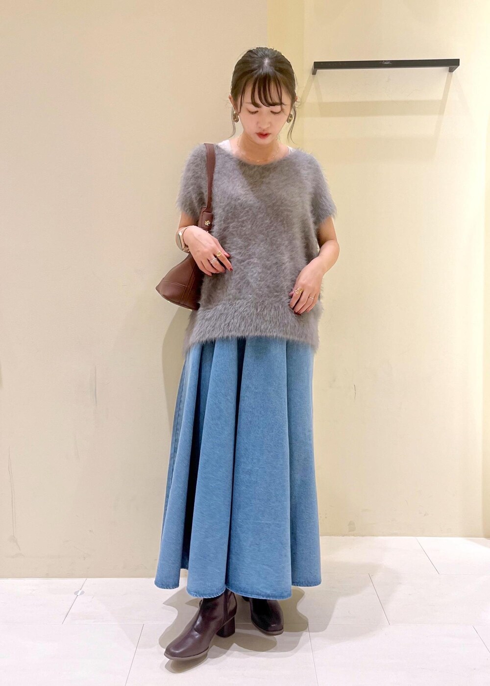 グレー系のタンクトップ、ブルー系のスカート、グレー系のベストを着用したレディースの秋コーディネートの2枚目の写真