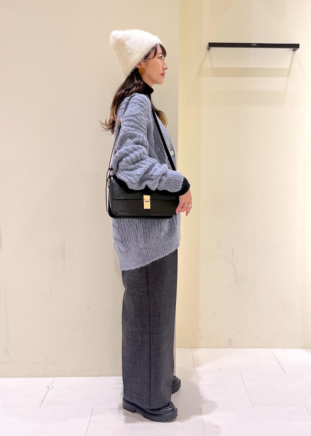 ブラック系のショルダーバッグ、ブラック系のニット/セーター、グレー系のスラックスを着用したレディースの秋コーディネートの2枚目の写真