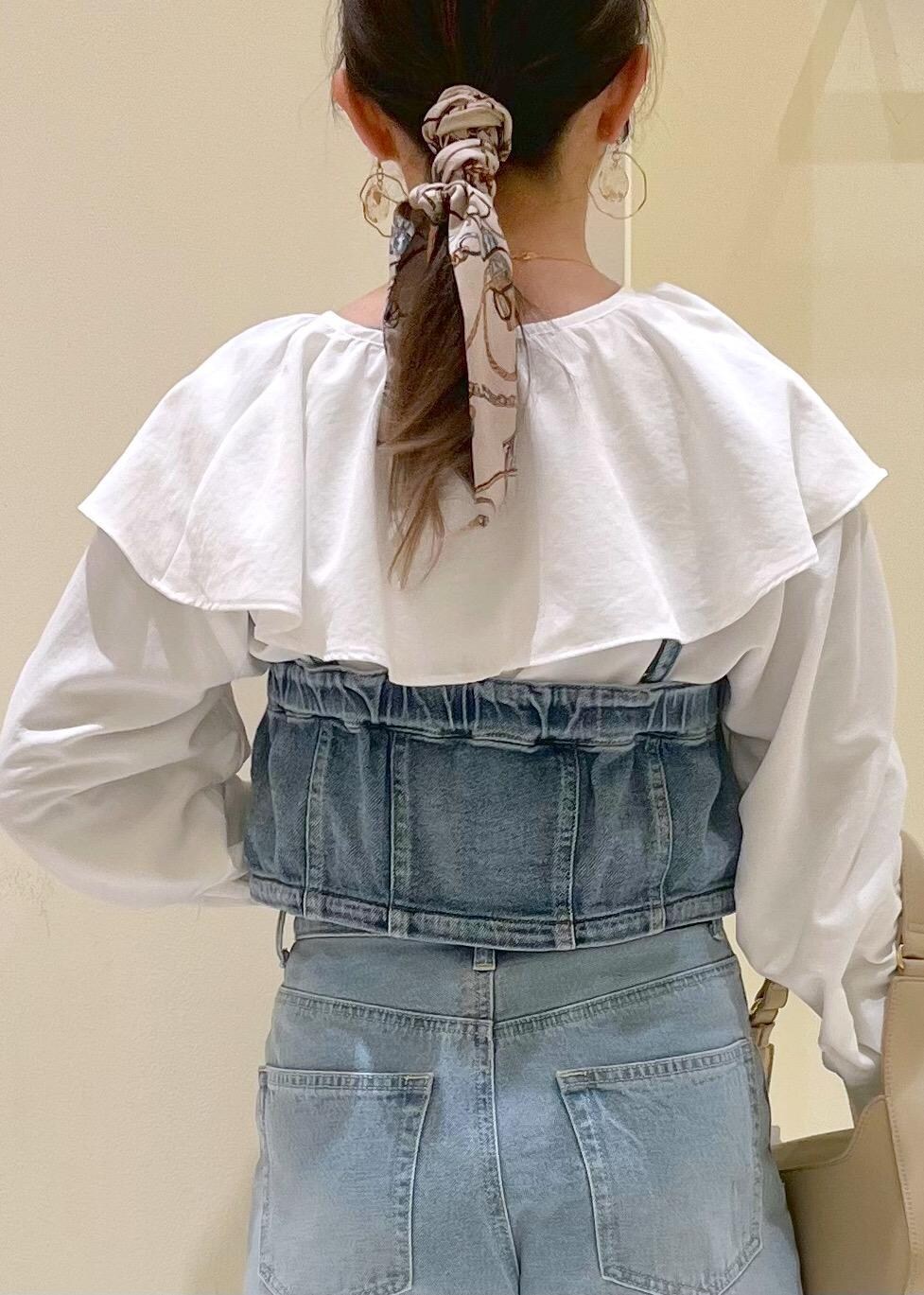 ベージュ系のハンドバッグ、ブルー系のデニムパンツ、ブルー系のベストを着用したレディースの春コーディネートの6枚目の写真