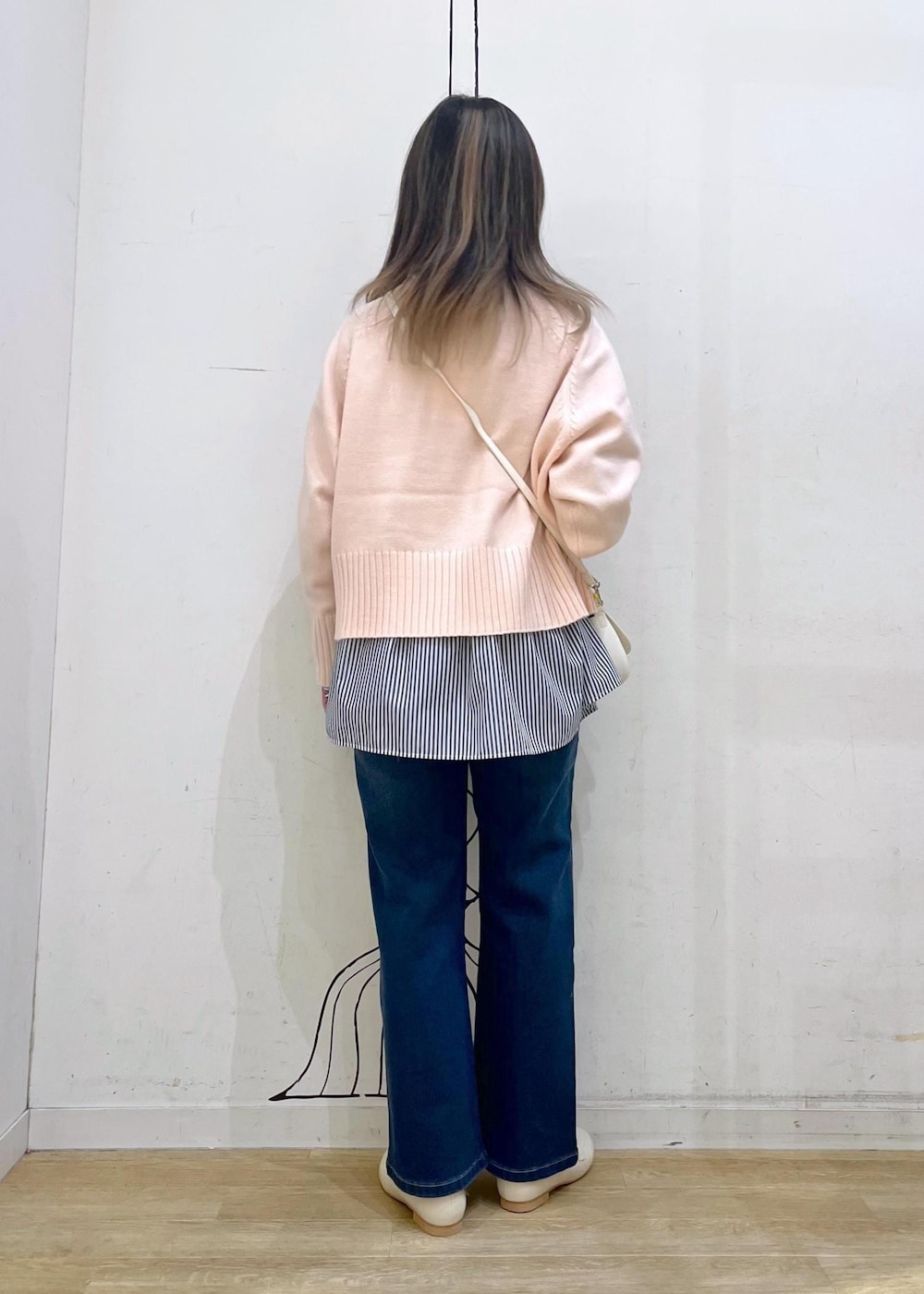 ピンク系のニット/セーター、ホワイト系のハンドバッグ、ブルー系のデニムパンツを着用したレディースの冬コーディネートの3枚目の写真