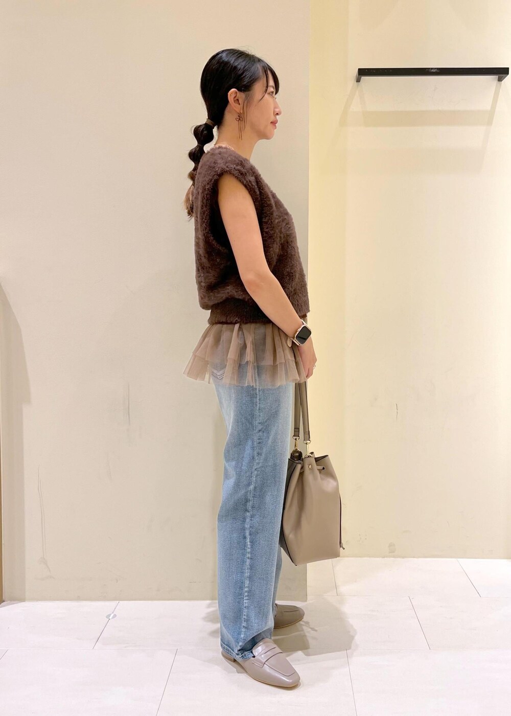 グレー系のローファー、ブルー系のデニムパンツ、ベージュ系のショルダーバッグを着用したレディースの夏コーディネートの3枚目の写真