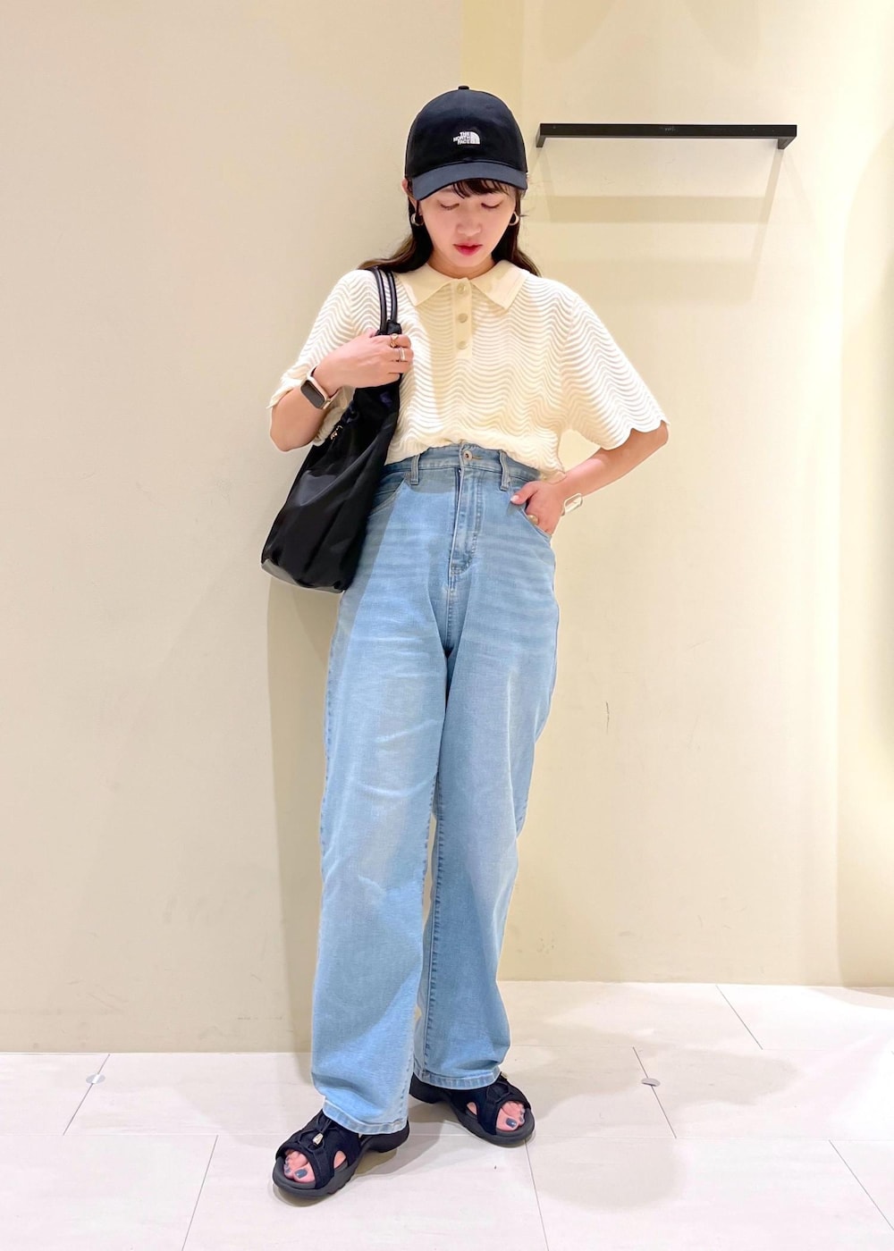 ブルー系のデニムパンツ、ホワイト系のニット/セーター、ブラック系のサンダルを着用したレディースの夏コーディネートの2枚目の写真