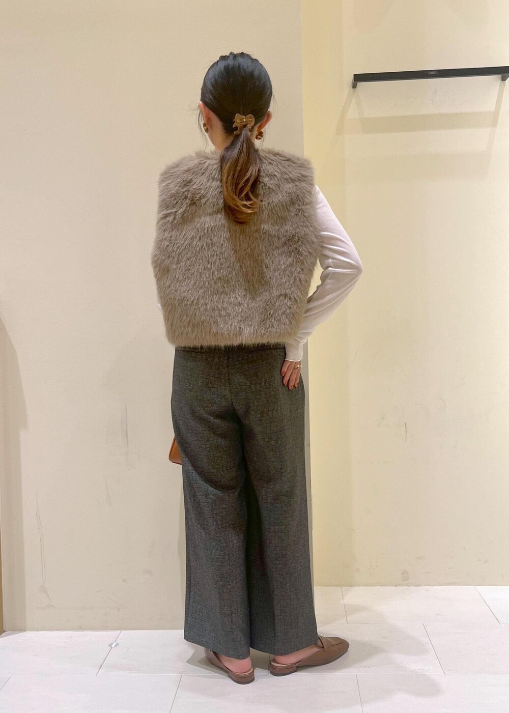 ブラウン系のベスト、ホワイト系のTシャツ/カットソー、グレー系のスラックスを着用したレディースの秋コーディネートの4枚目の写真