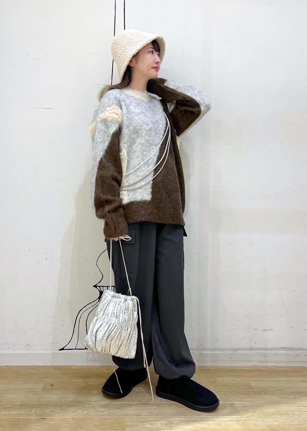 グレー系のカーゴパンツ、シルバー系のショルダーバッグ、ブラウン系のニット/セーターを着用したレディースの秋コーディネートの2枚目の写真