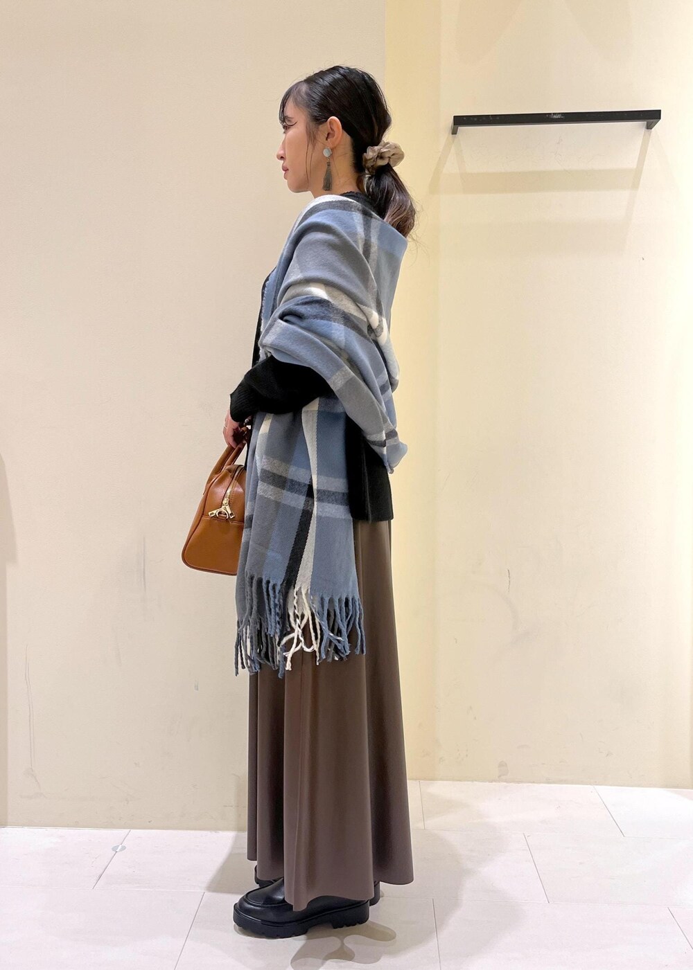 ブラウン系のスカート、ブラウン系のボストンバッグ、ブラック系のニット/セーターを着用したレディースの秋コーディネートの4枚目の写真