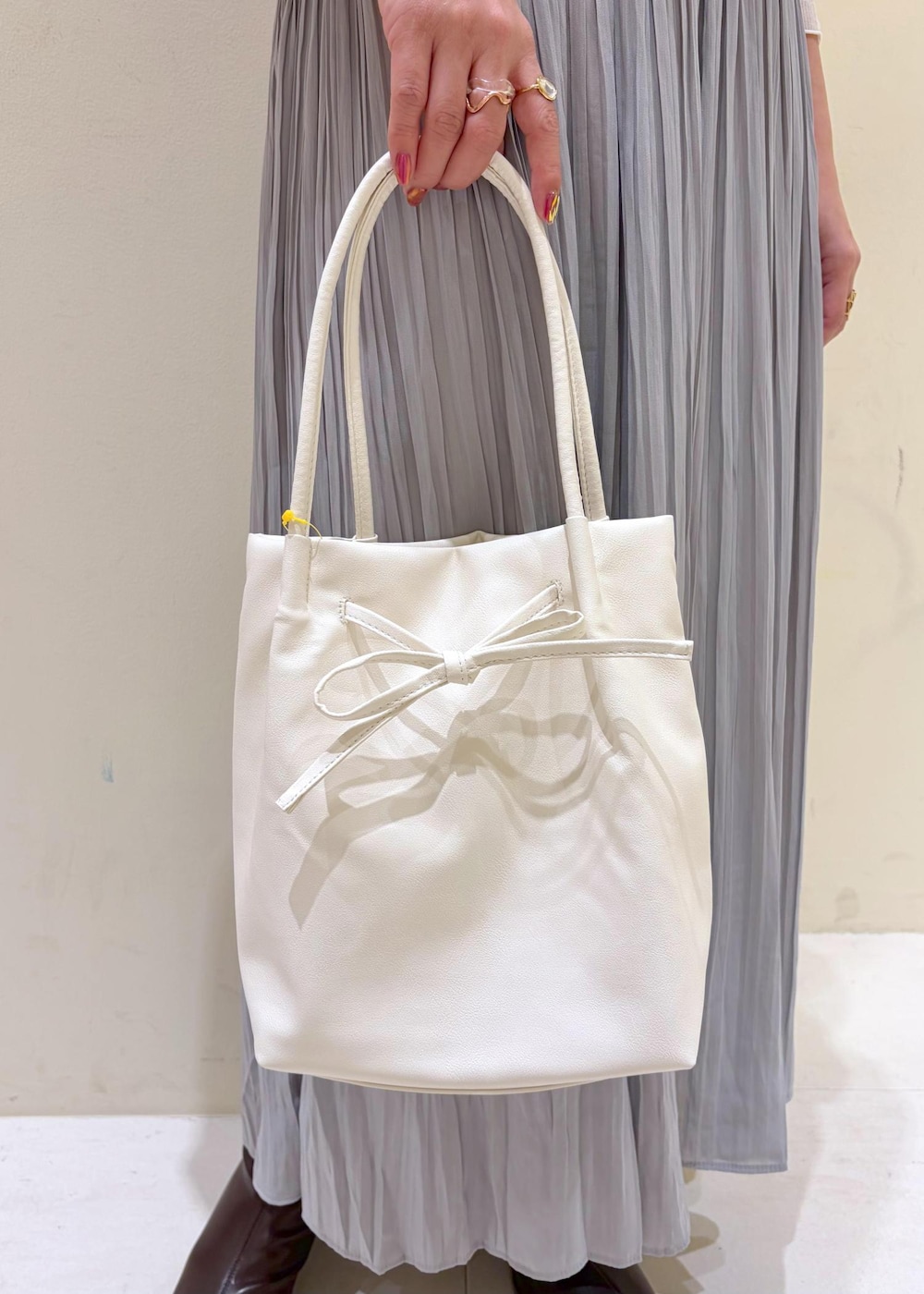 グレー系のスカート、ベージュ系のカーディガン/ボレロ、ホワイト系のトートバッグを着用したレディースの冬コーディネートの9枚目の写真