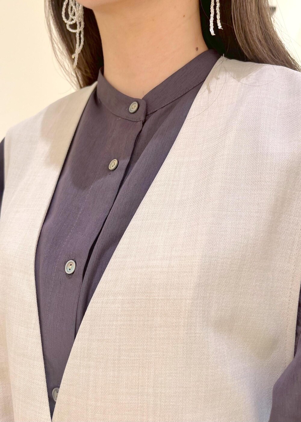 イエロー系のローファー、ブラック系のハンドバッグ、ベージュ系のベストを着用したレディースの春コーディネートの6枚目の写真